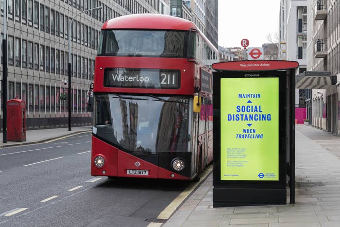 London double-decker bus beside a sign urging to maintain social distancing