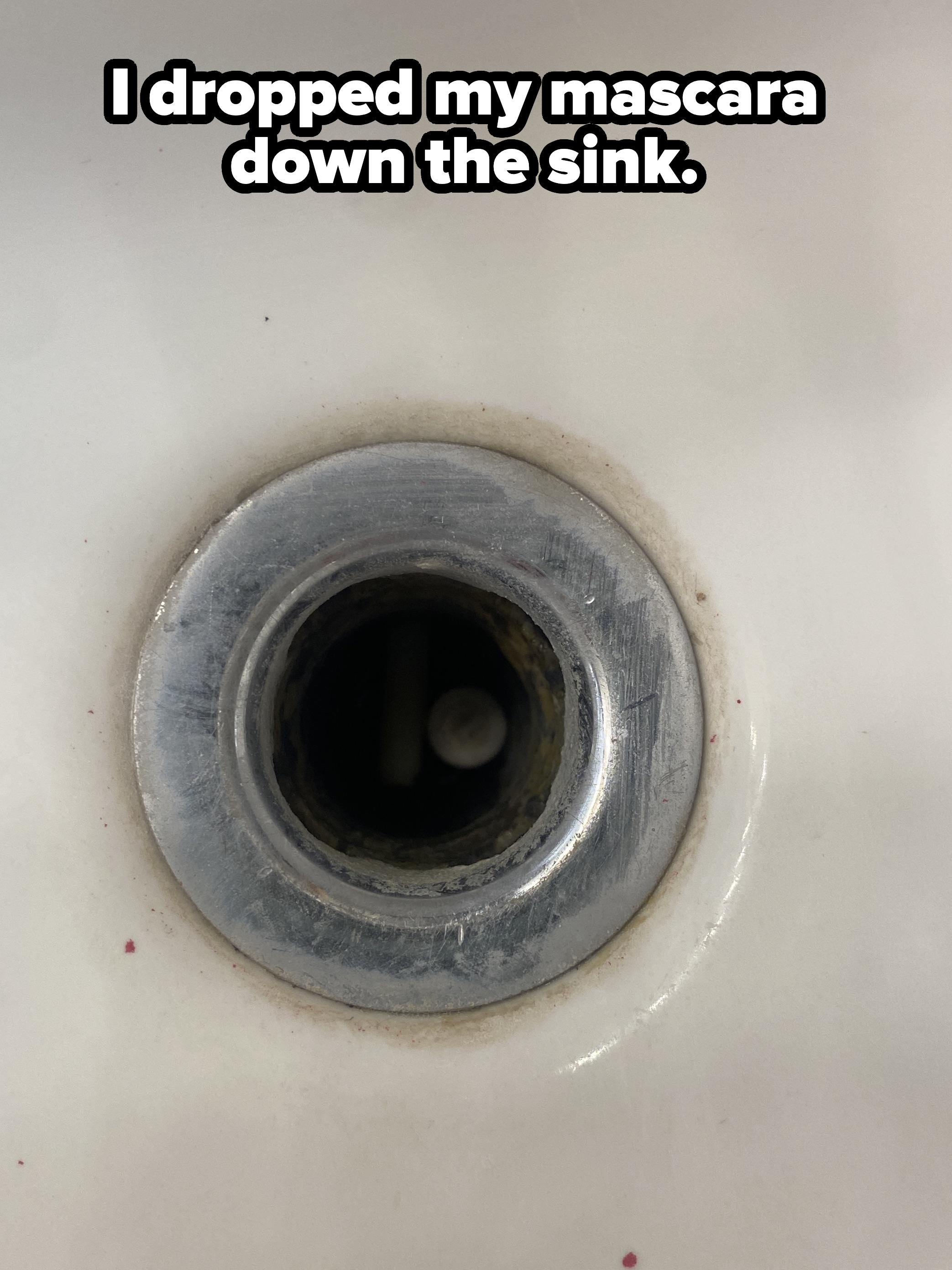 Close-up of a sink drain with a tube of mascara barely visible at the bottom