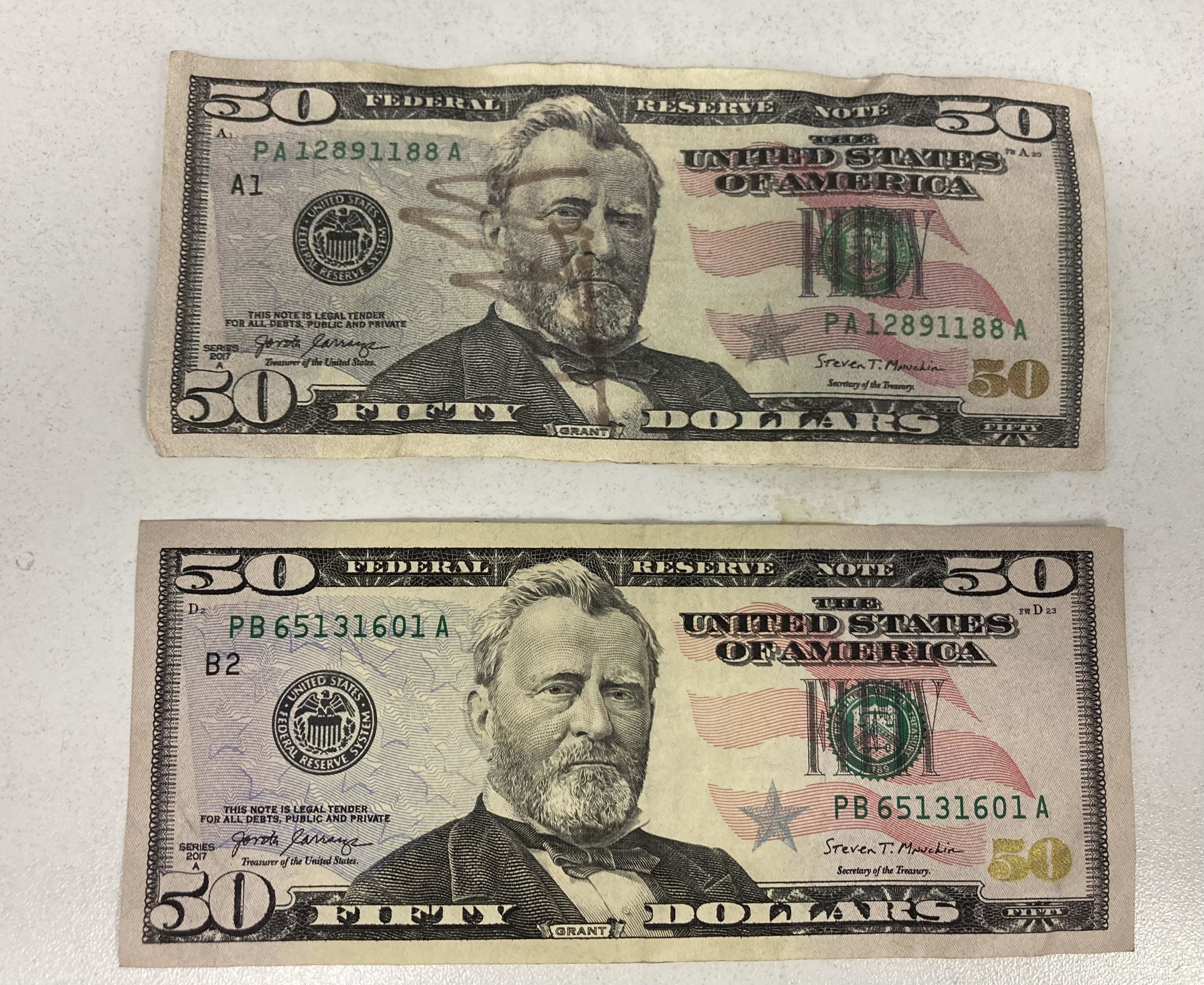 Two US $50 bills, one above the other, with slight design differences