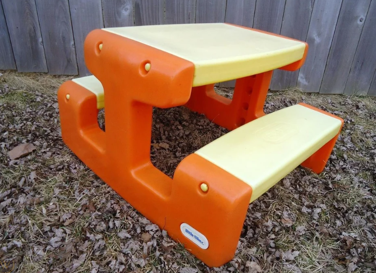 A small, plastic children&#x27;s picnic table with attached benches