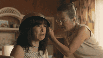 GIF of a woman cutting her daughter&#x27;s hair in &quot;PEN15&quot;