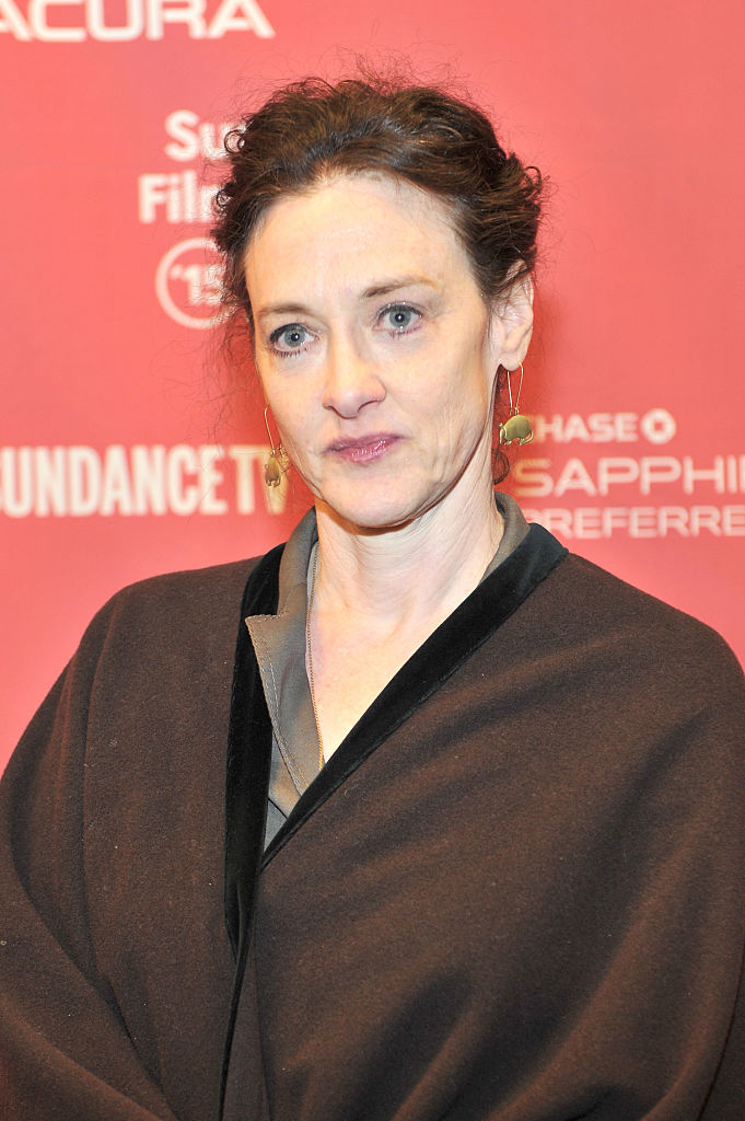 Joan on the red carpet in a  robe-style outfit with gold earrings
