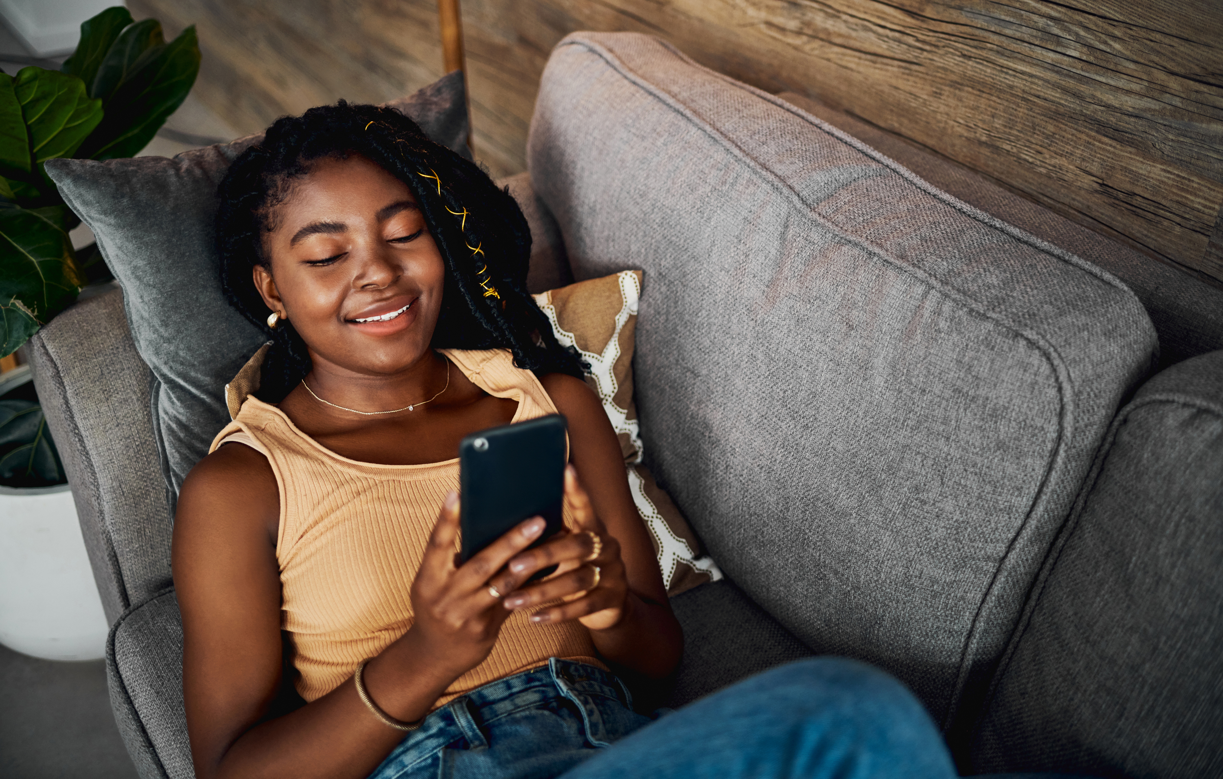 Woman lounging on a sofa, smiling at her phone