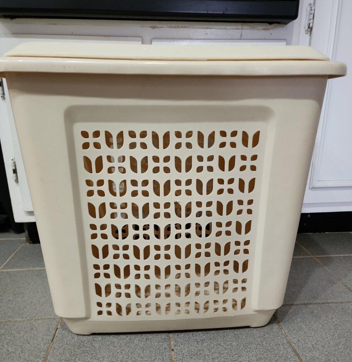Beige laundry basket in front of a kitchen cabinet