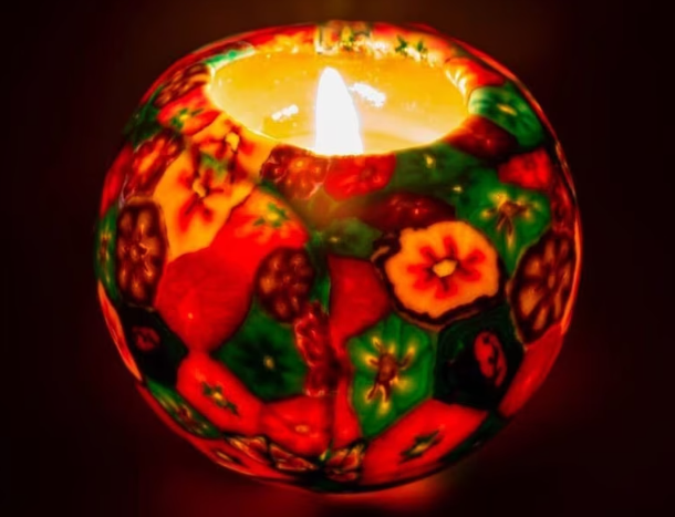 A lit spherical candle with floral patterns