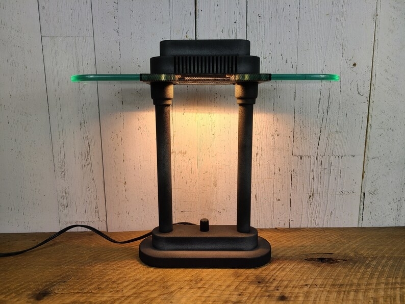 Retro levitating lamp with illuminated green edge, on a wooden surface against a white plank backdrop