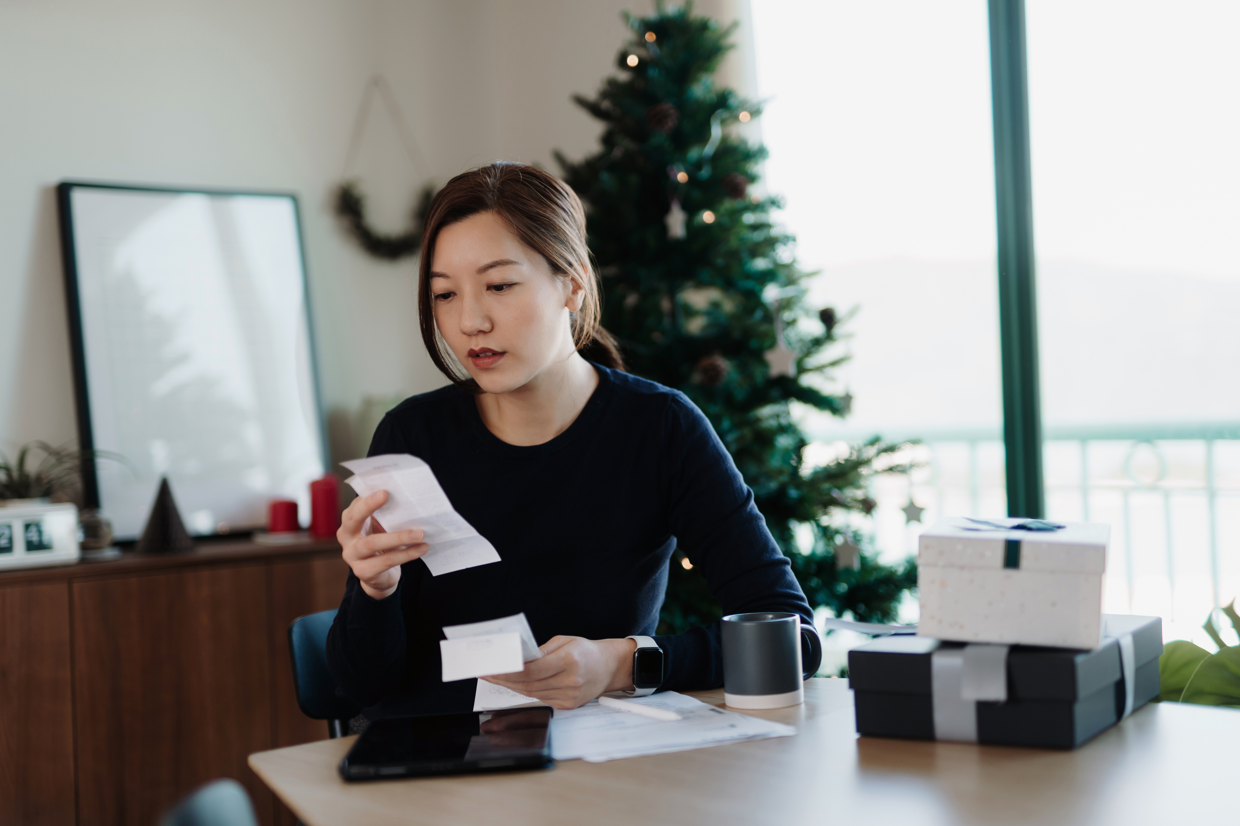Woman reviewing financial documents at a desk with gift boxes nearby