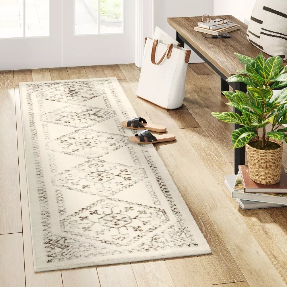 A runner rug with geometric patterns placed in a room beside a tote bag and sandals