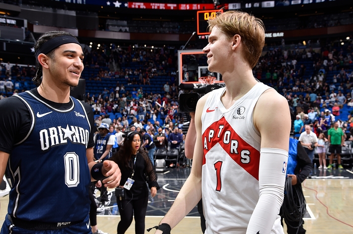 Two basketball players from opposing teams are having a friendly chat on the court post-game
