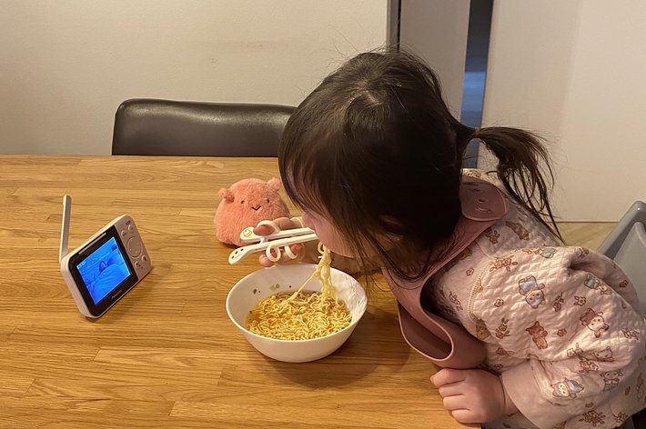 子供が動画を見ながらラーメンを食べている様子