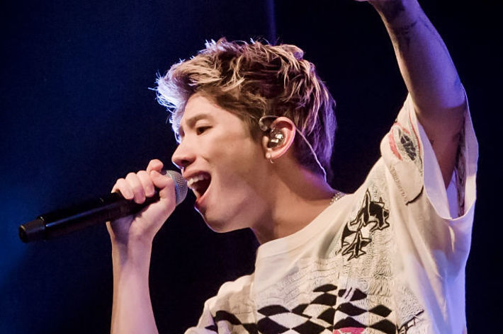 歌手がマイクで歌い、ピースサインをしています。