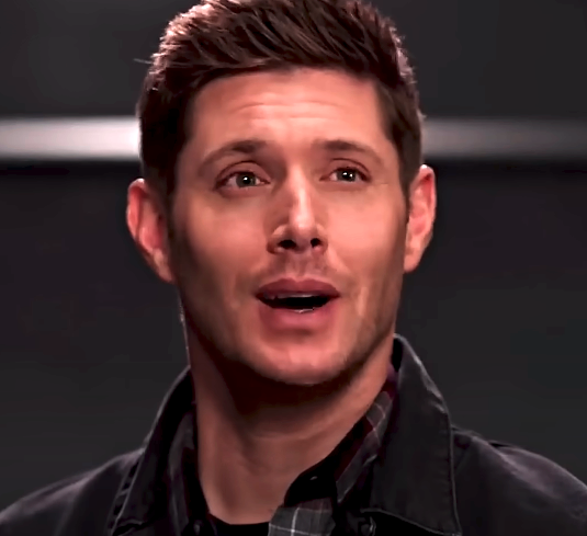Jensen Ackles in a plaid shirt and jacket, smiling slightly, from the TV show Supernatural
