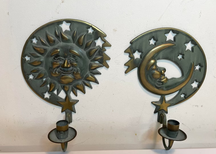 Two wall-mounted candle holders with sun and crescent moon designs