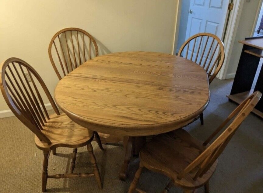 A round wooden table with four matching chairs in an interior setting