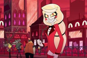 Charlie from Hazbin Hotel stands confidently in red suit attire with background characters and a city backdrop