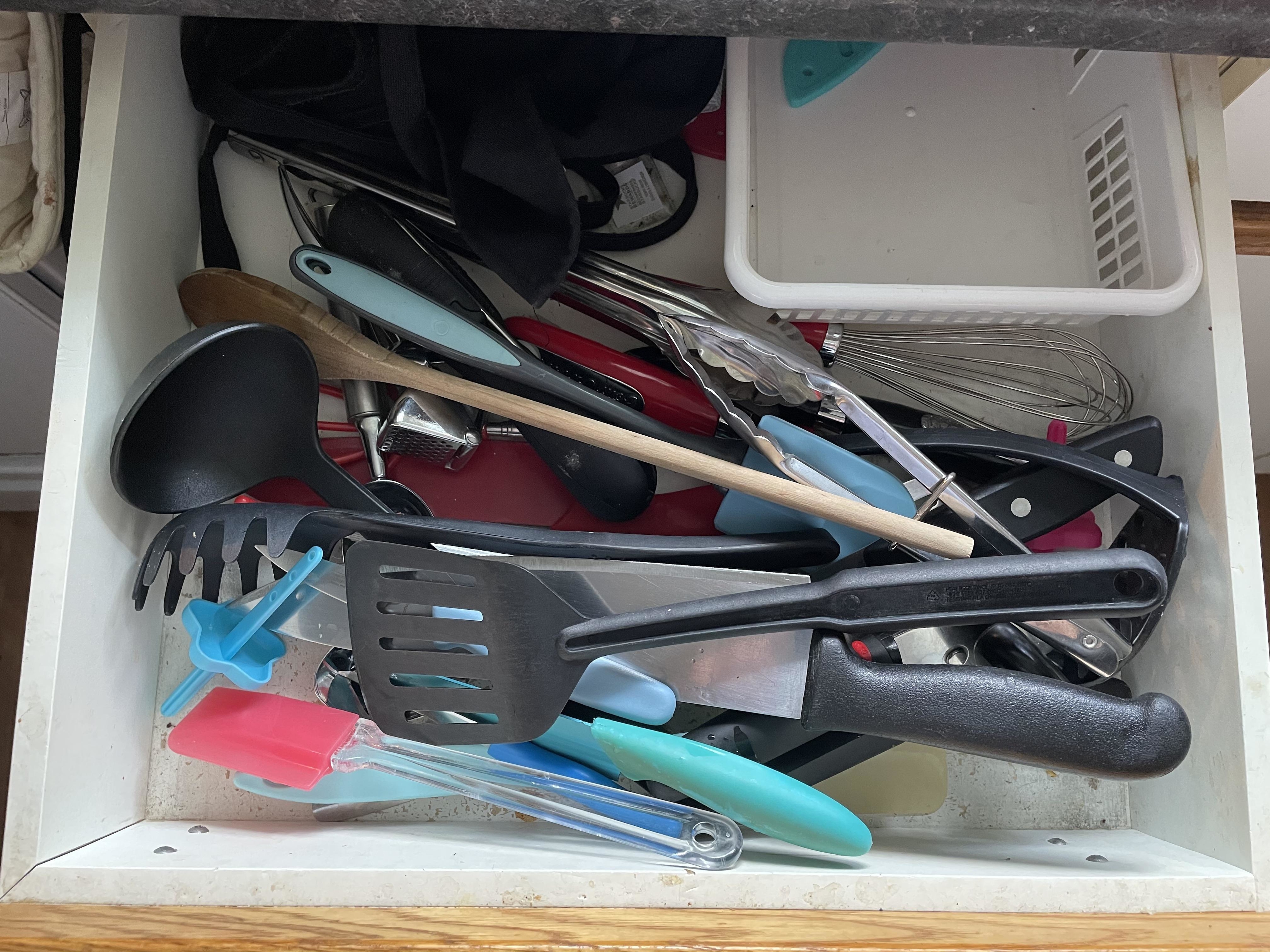 Assorted kitchen utensils in a cluttered drawer, including spatulas and whisks