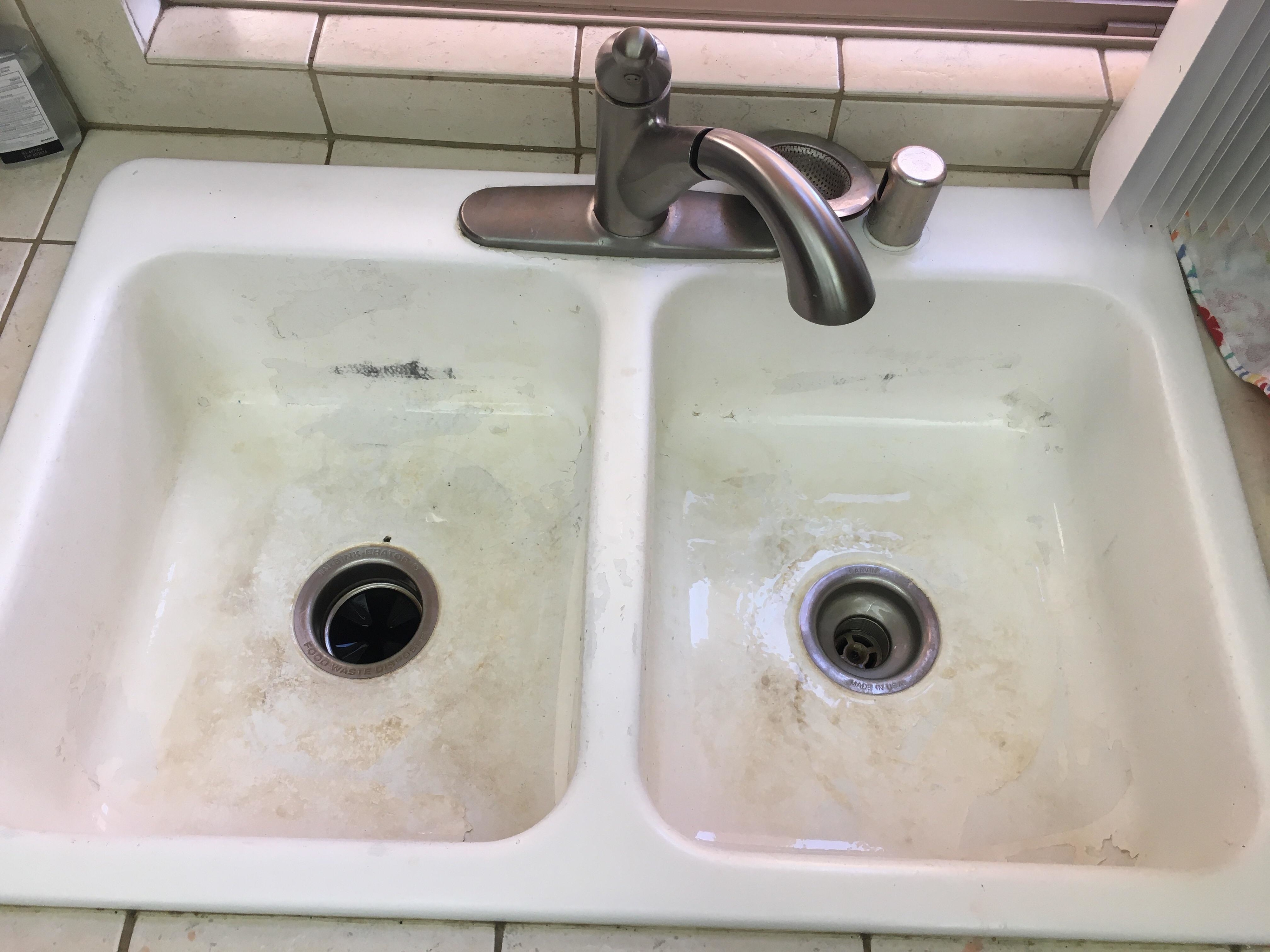 A dirty double kitchen sink with visible grime and no dishes