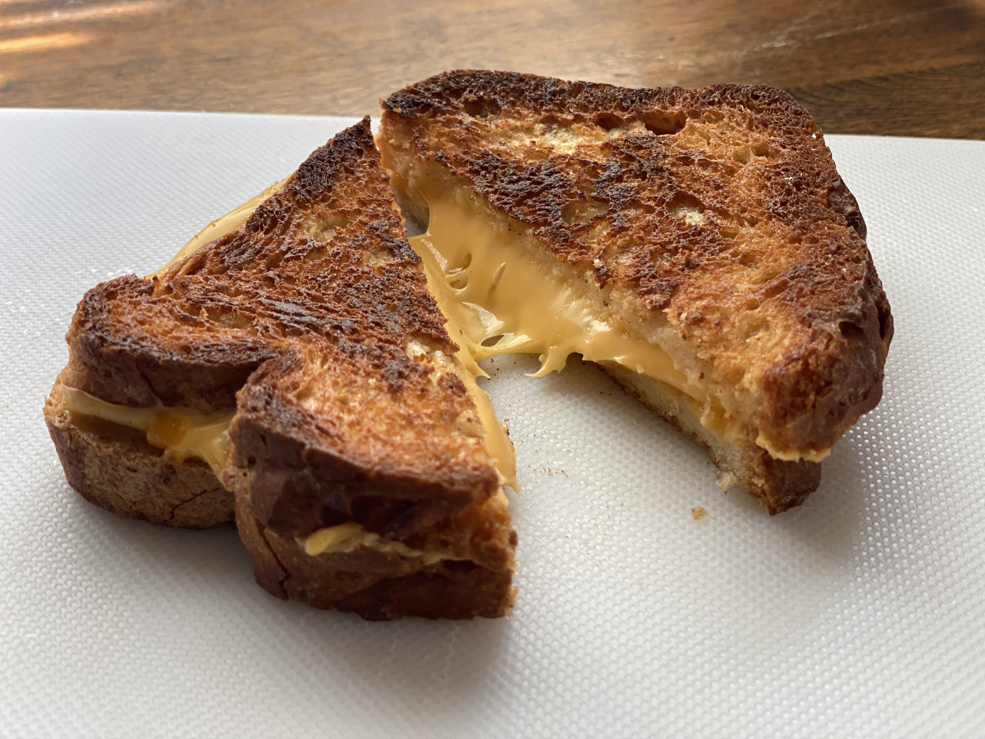 Grilled cheese sandwich cut in half with melted cheese on a plate