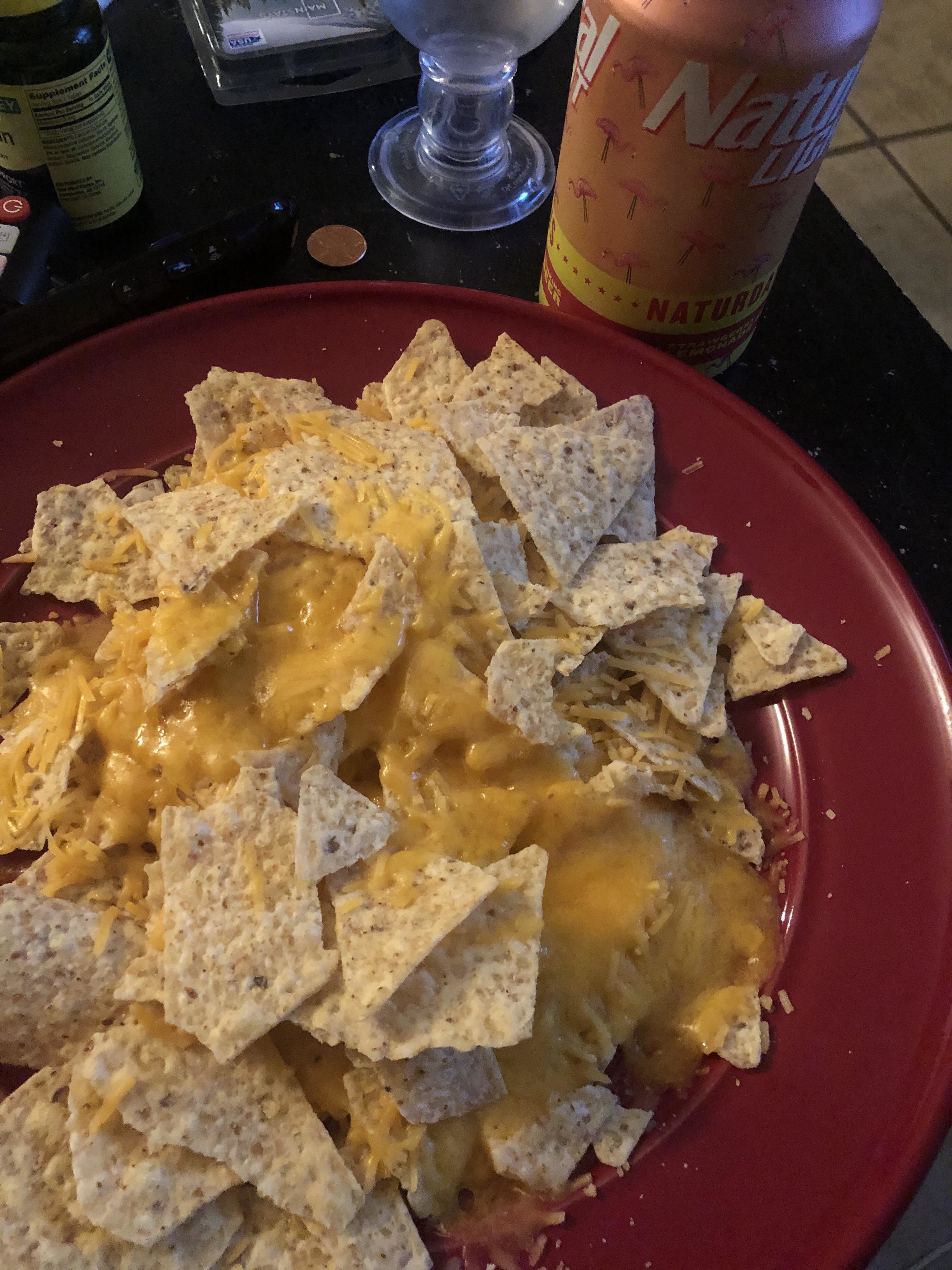 Plate of nachos with melted cheese, next to a can of Natural Light beer
