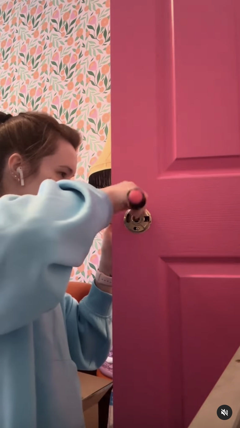 Kaarin works on installing a new doorknob for a bright pink door in her home