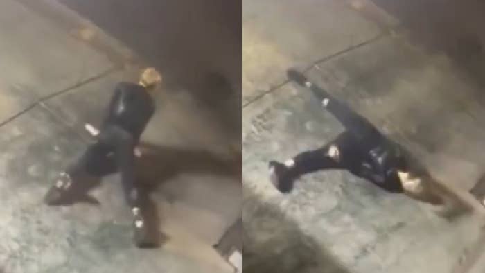 Person in a dark suit and boots slips and falls on a sidewalk at night