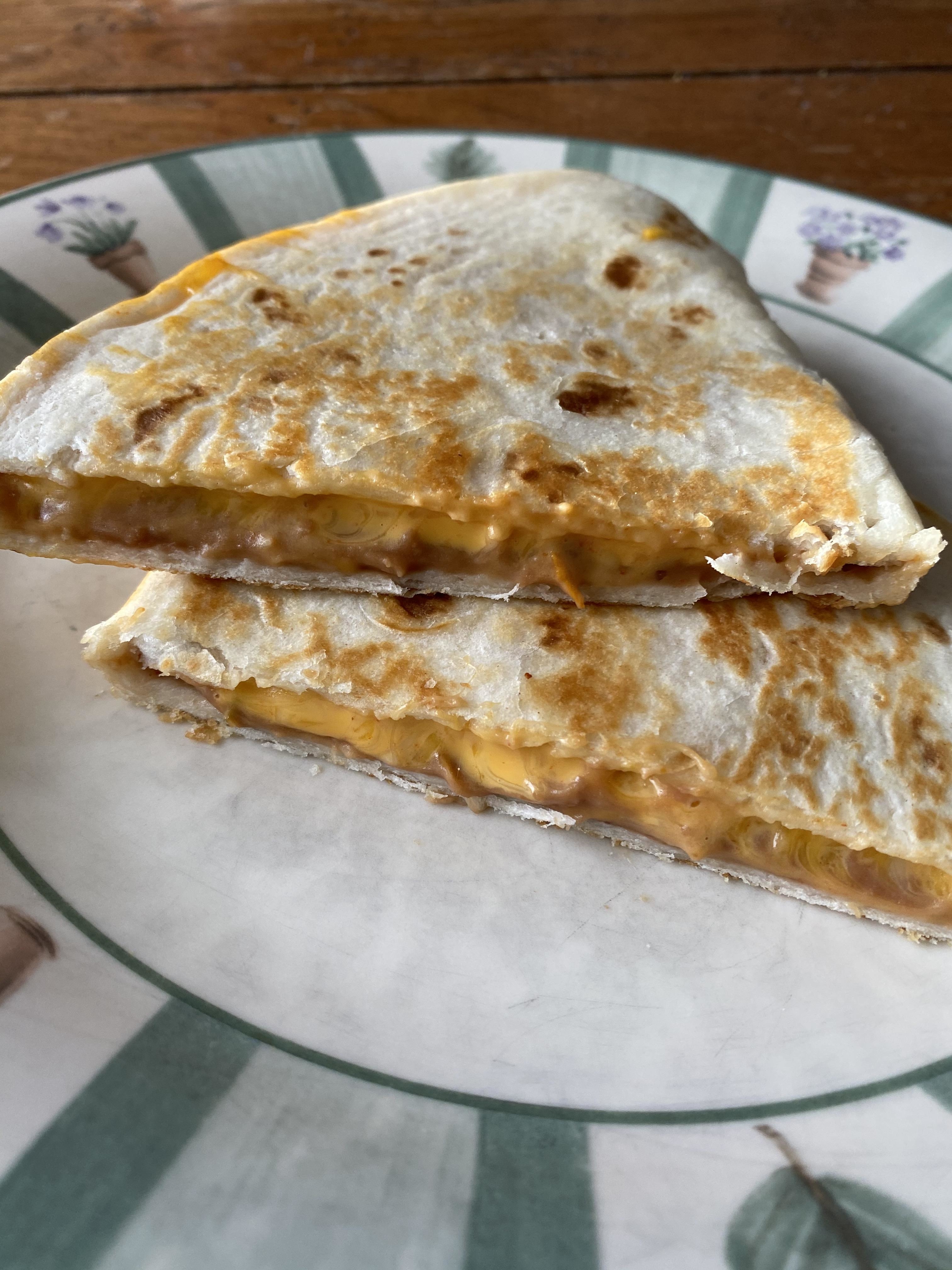 A cheese quesadilla cut into quarters on a plate