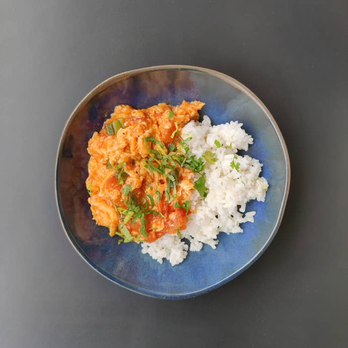 Plate with rice and creamy tomato-based chicken dish garnished with herbs