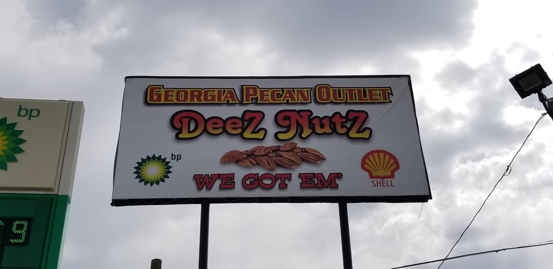 Billboard for Georgia Pecan Outlet named &quot;Deez Nutz&quot; with slogan &quot;WE GOT &#x27;EM&quot; flanked by BP and Shell logos