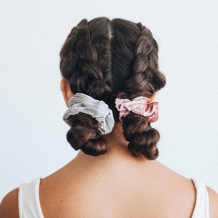 Person with double braids secured with scrunchies, suitable for a shopping or fashion context