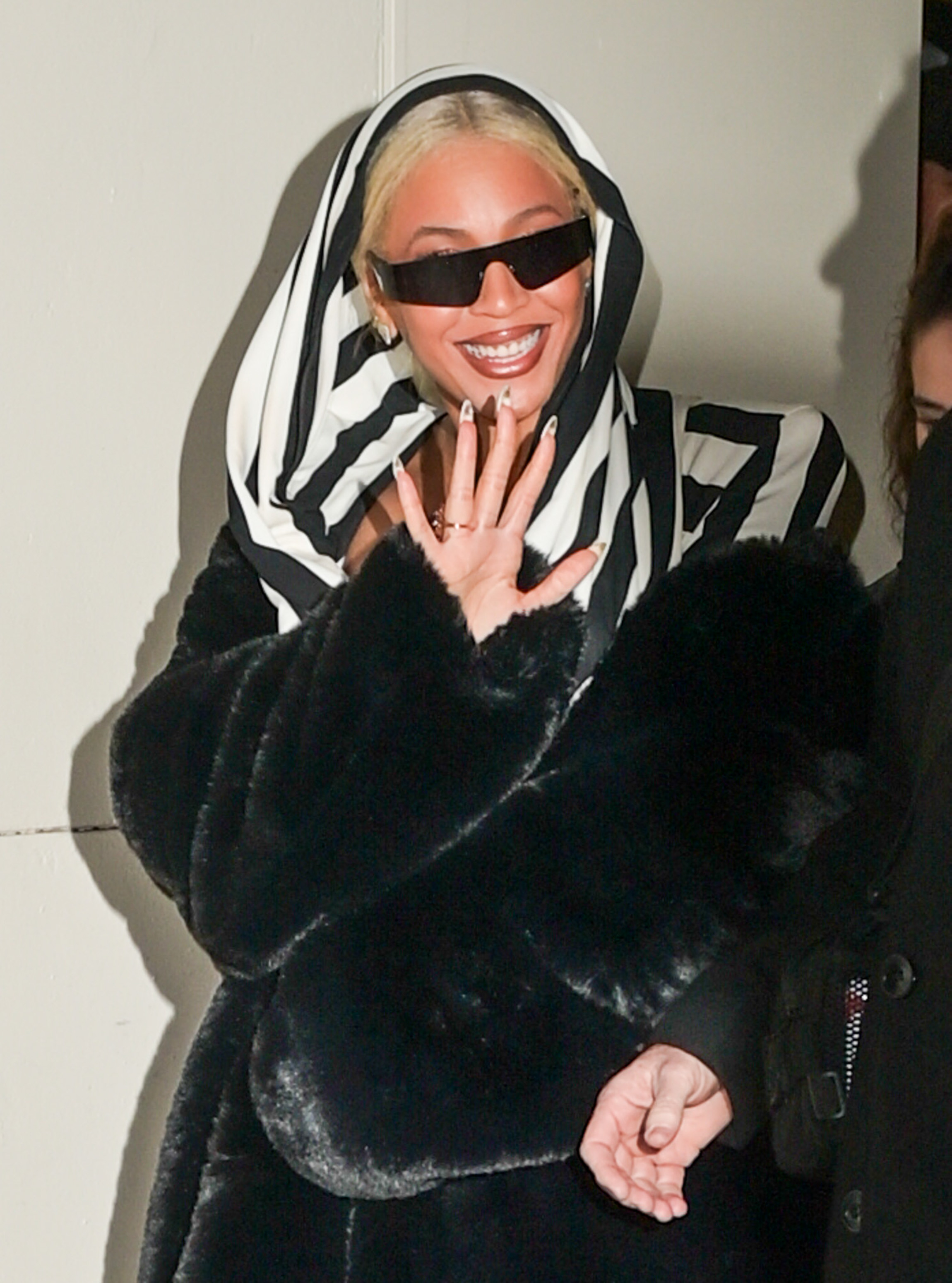 Closeup of Beyoncé waving as she exits a business