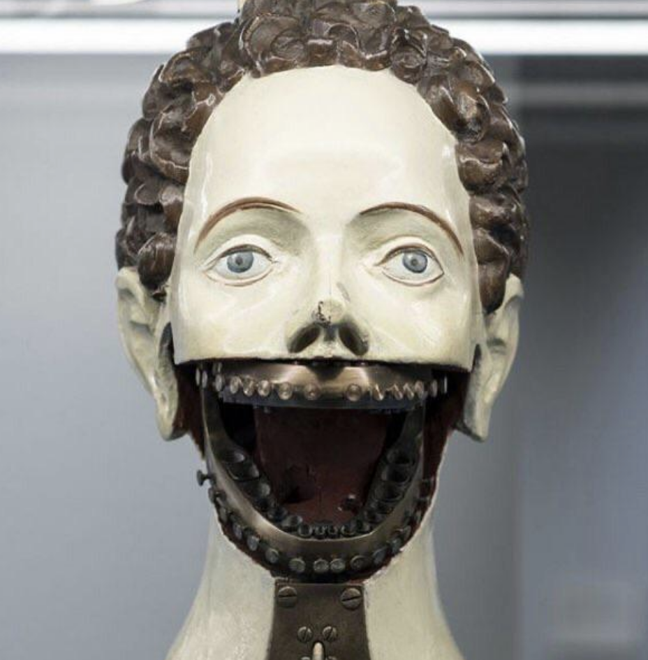 Close-up of an antique automaton head with an open mouth revealing inner gears