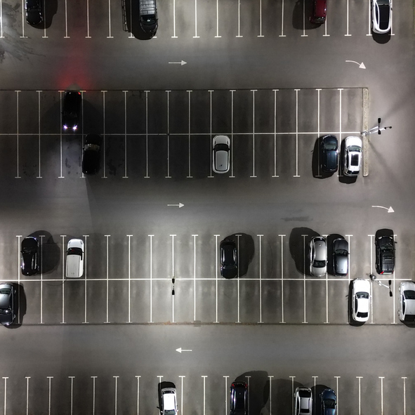 Overhead view of a parking lot at night with several cars parked in delineated spaces