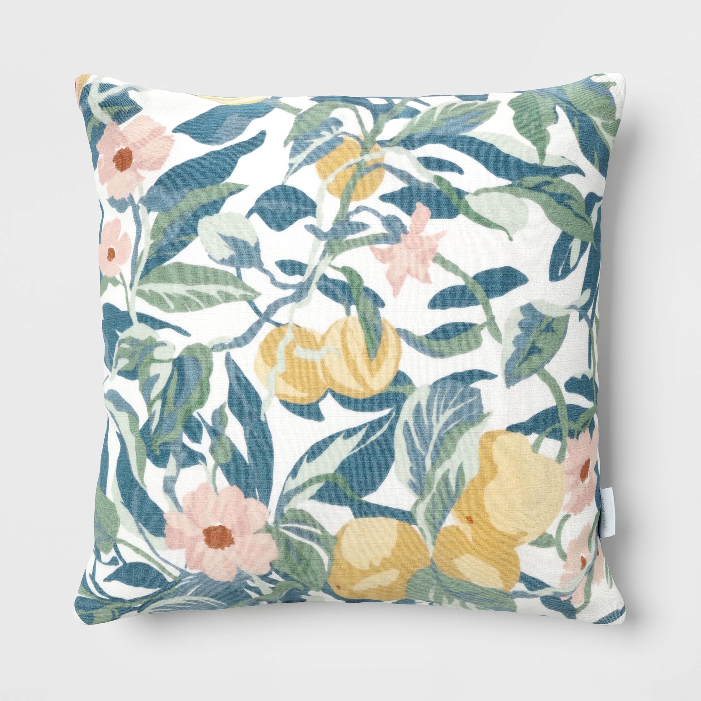 A decorative pillow with a floral and lemon pattern