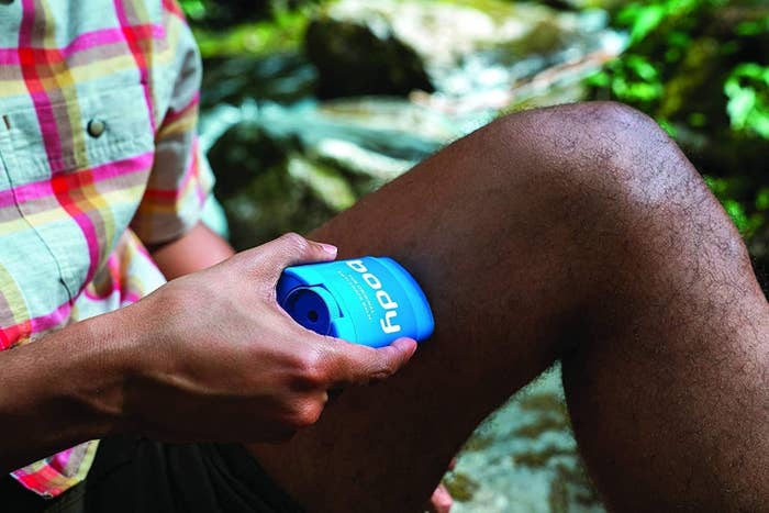 Person holding blue anti-chafe balm outdoors