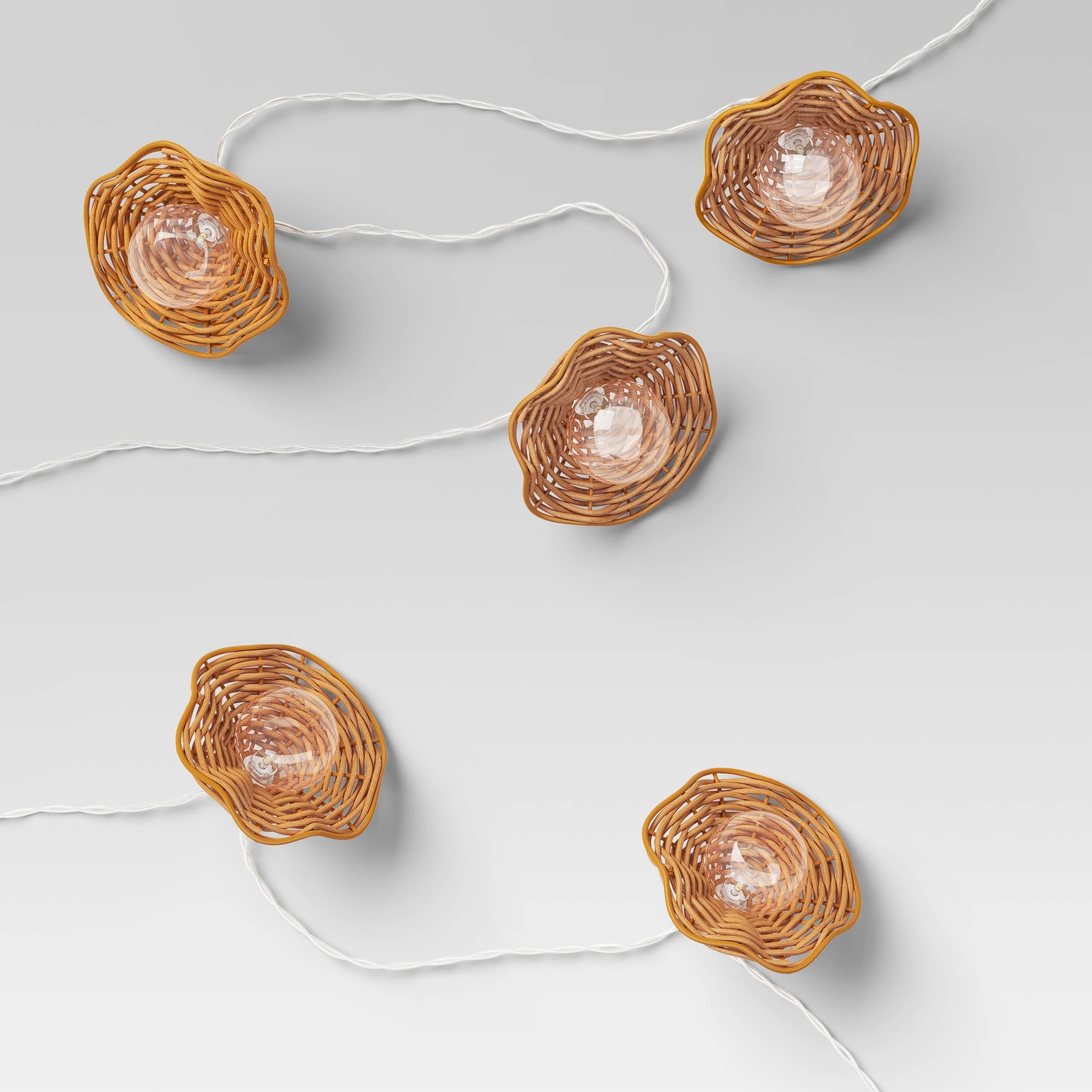 String lights with four wicker-covered bulbs on a plain background
