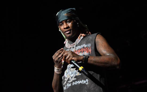 Rapper on stage with microphone, wearing bandana and graphic tank top