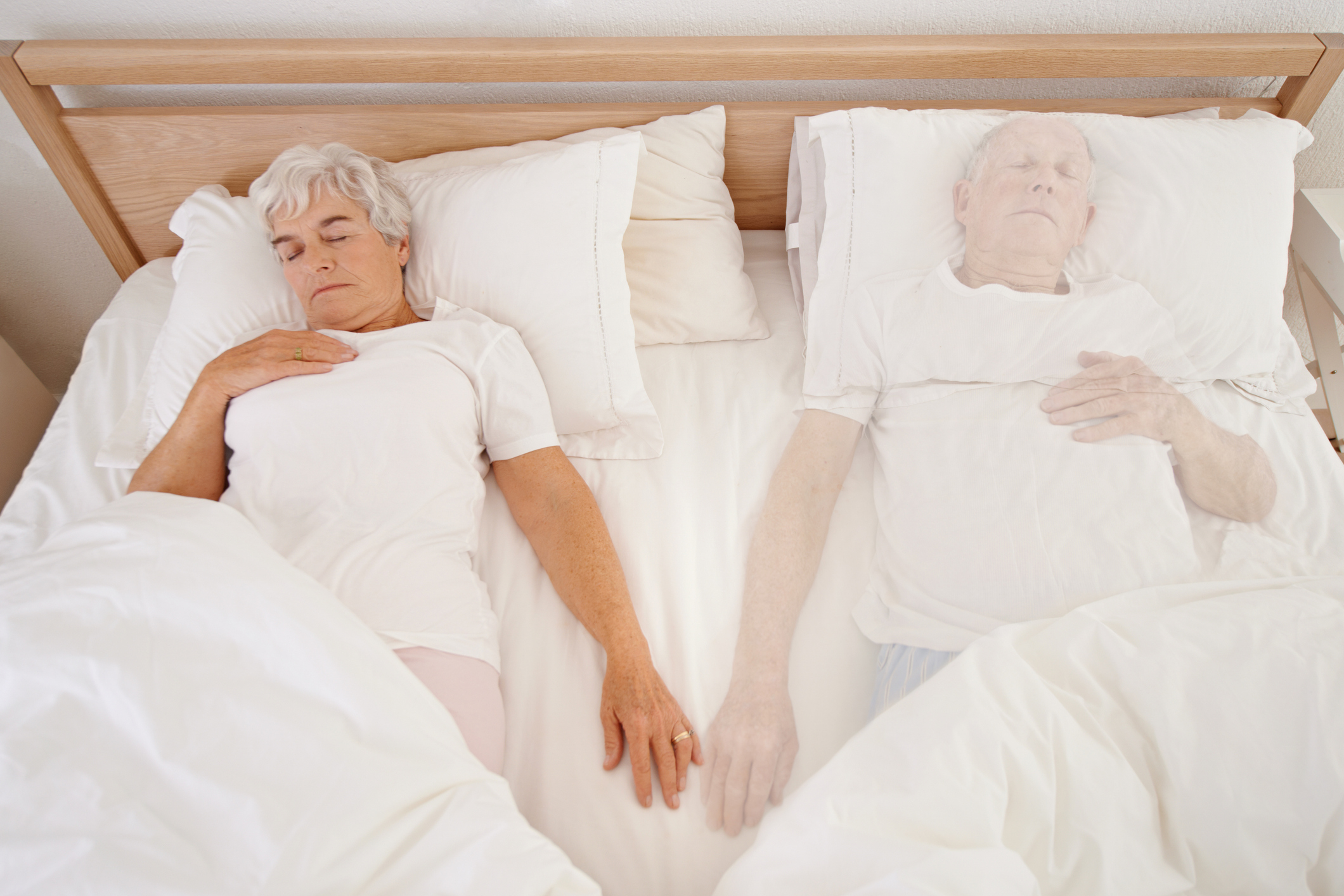 older woman sleeping in a bed next to the ghost of her husband