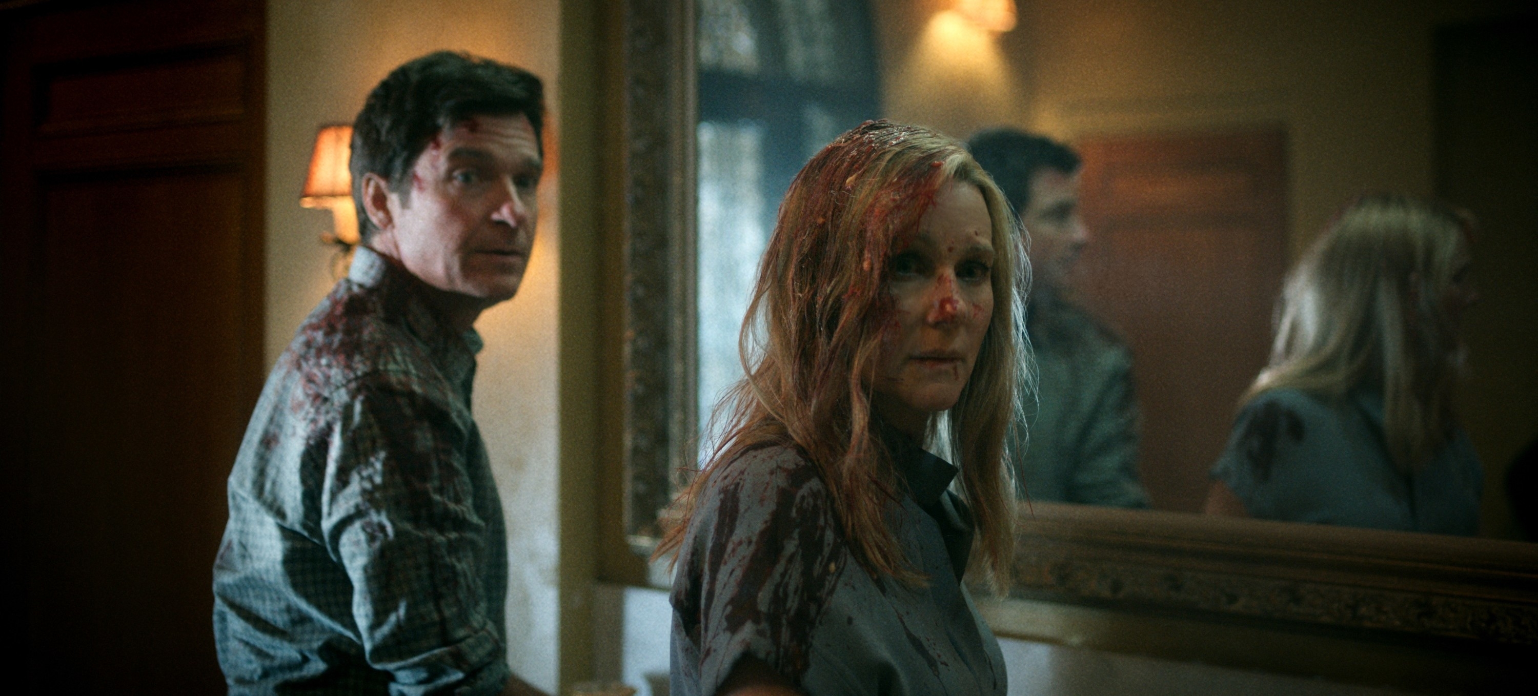 Two actors portraying distress, with simulated blood on their faces and clothing, in a dramatic scene