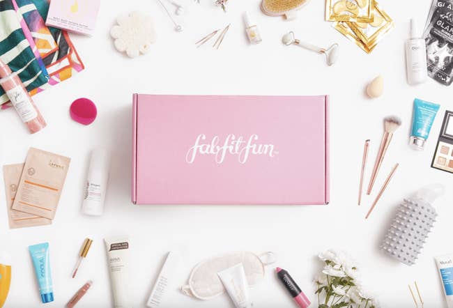 A FabFitFun subscription box surrounded by an array of beauty products and makeup tools