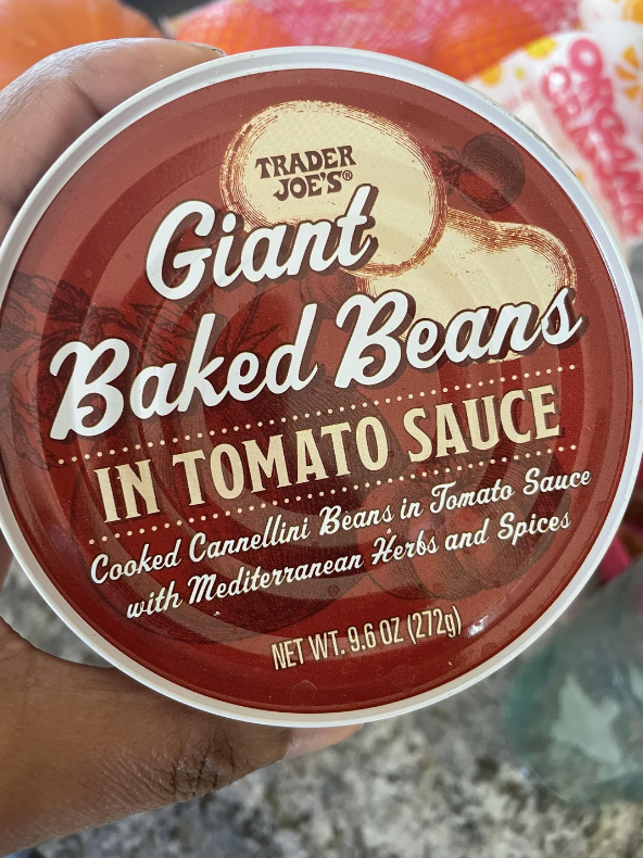 Hand holding a can of Trader Joe&#x27;s Giant Baked Beans in tomato sauce with Mediterranean herbs and spices