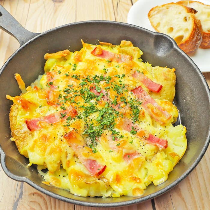 鉄製フライパンに入ったポテトとパンが写っています。