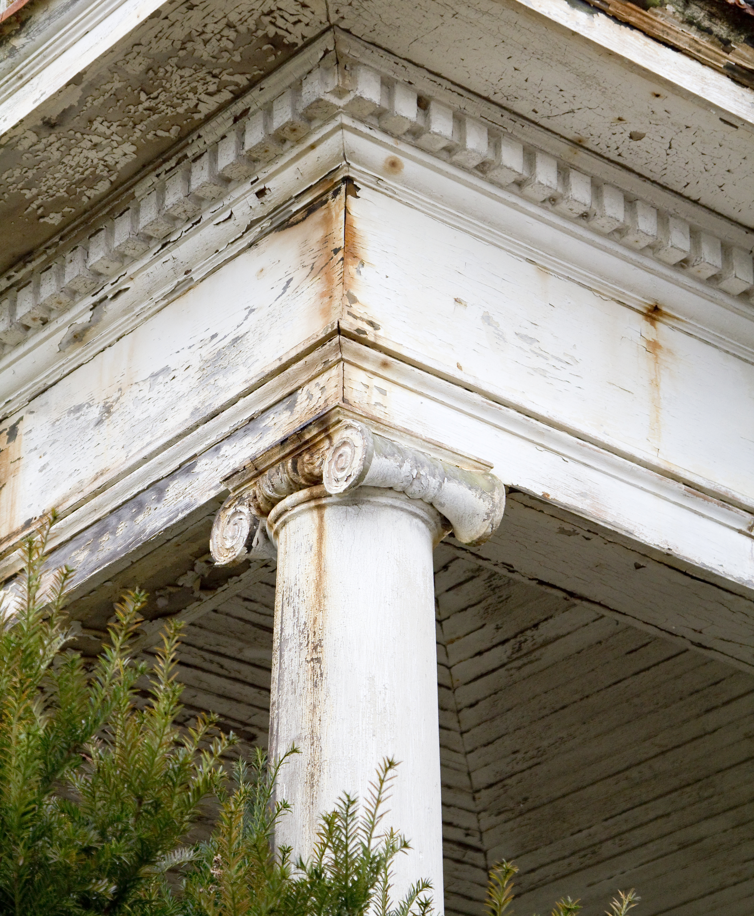 Close-up of a weathered white classical column with decorative capital, part of an old building&#x27;s architecture