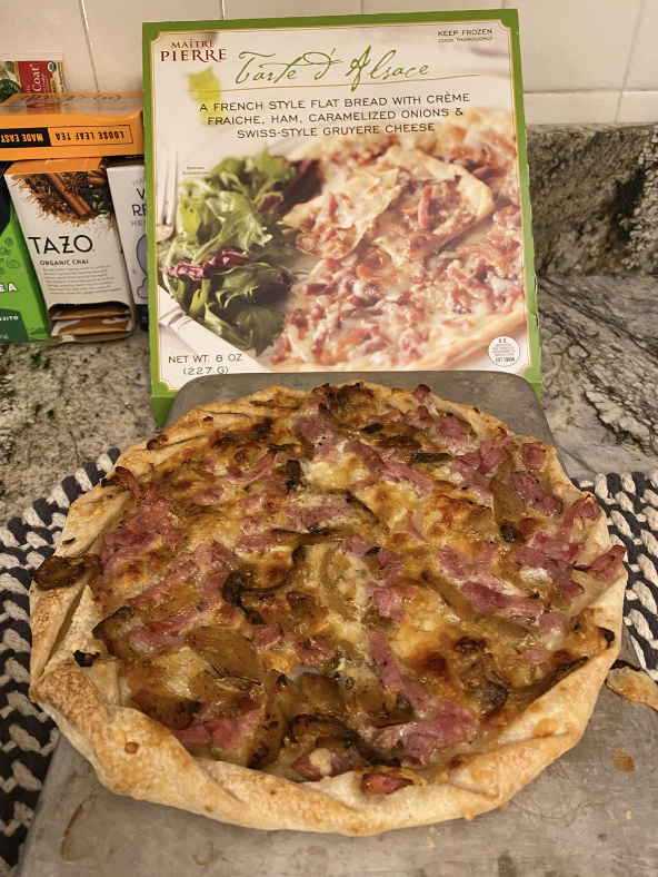 Prepared Tarte d&#x27;Alsace flatbread with ham and caramelized onions on a kitchen counter next to its packaging