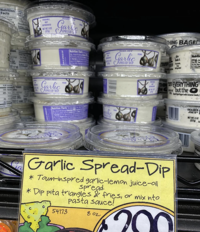 Garlic spread-dip containers on a store shelf with a label describing the product as &quot;Toum-inspired garlic-lemon juice-oil spread,&quot; priced at $2.99
