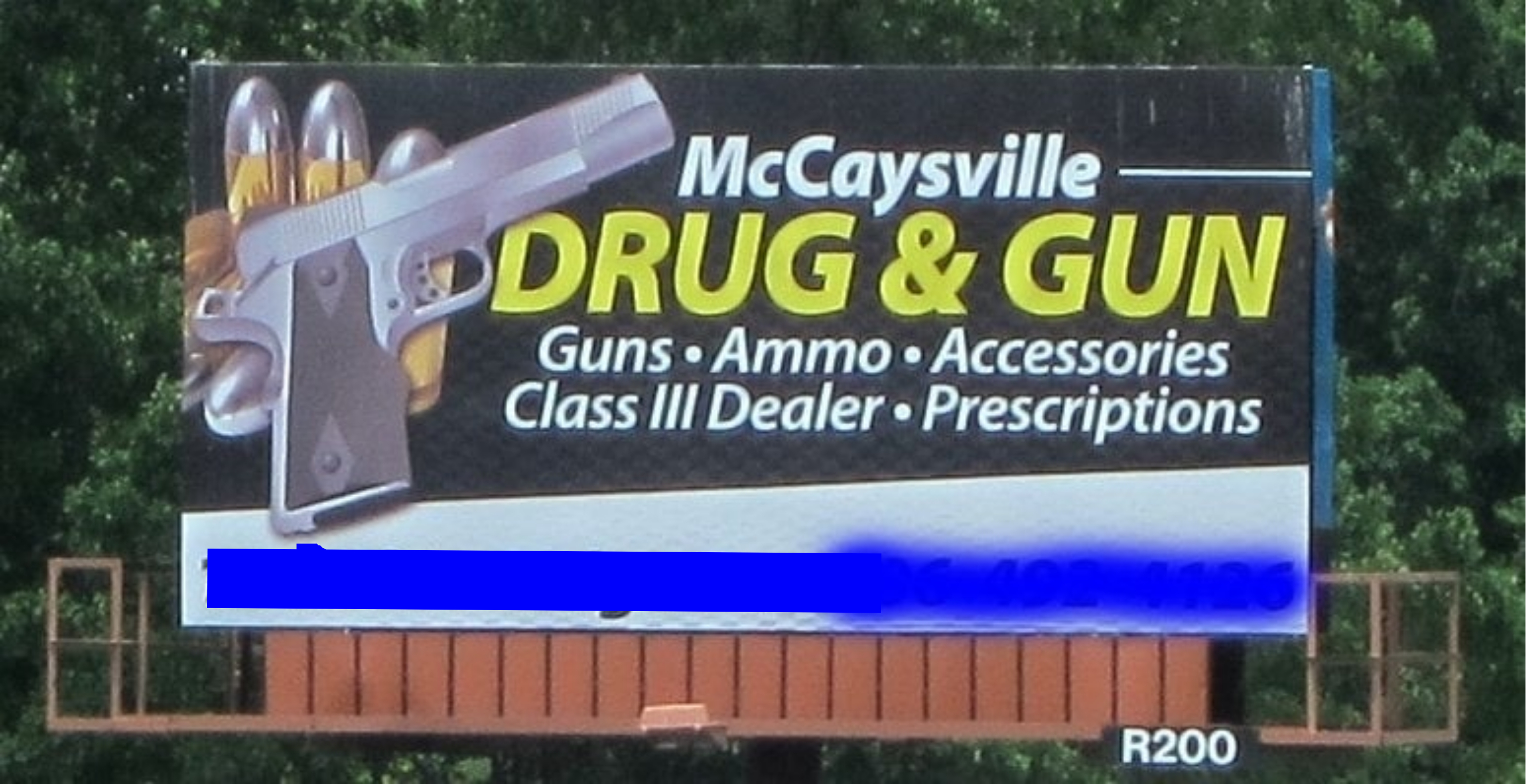 Billboard for McCaysville Drug &amp;amp; Gun store advertising guns, ammo, accessories, and prescriptions with a graphic of a pistol and pills. Address obscured