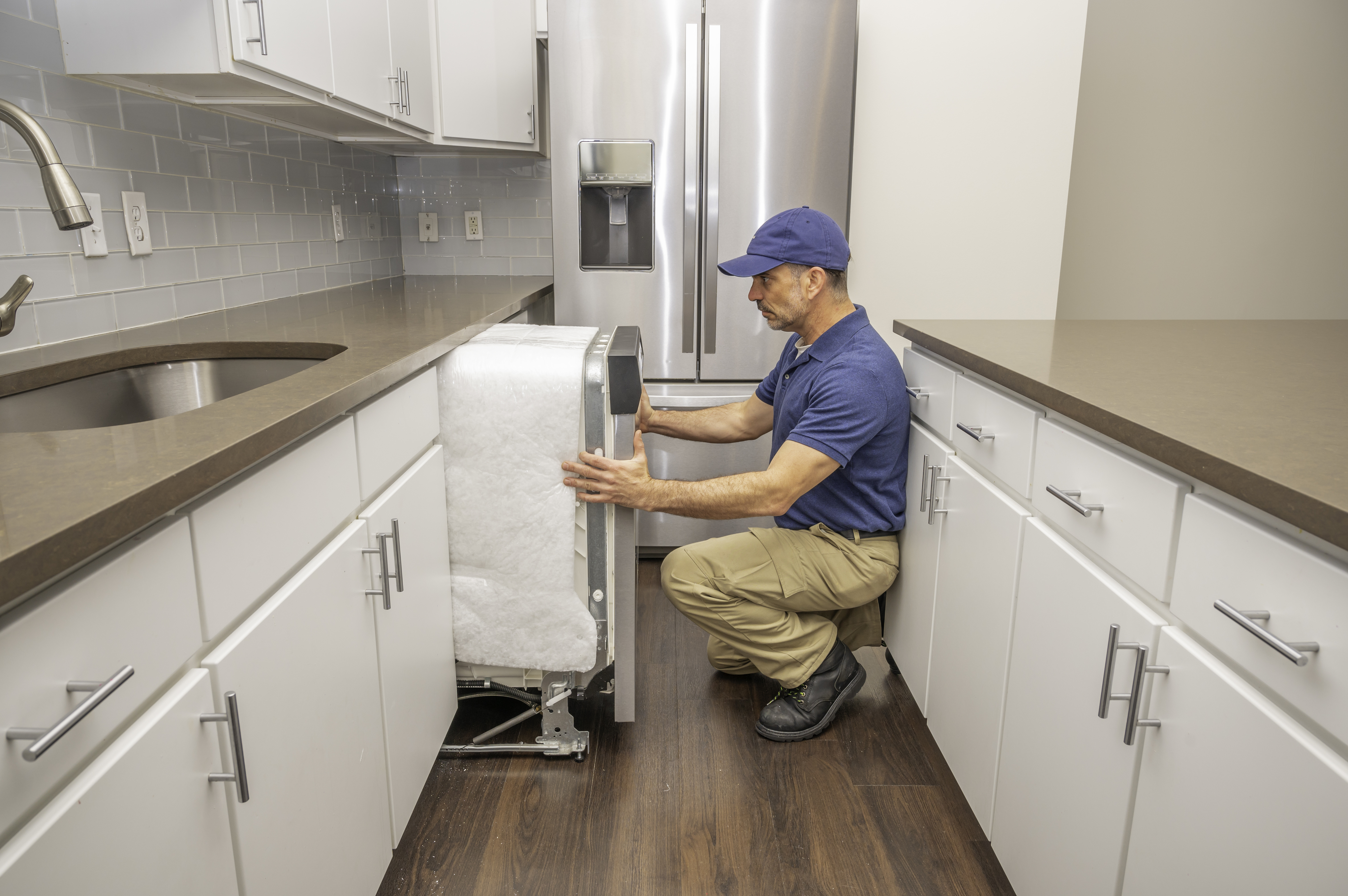 Technician installing dishwasher in a kitchen