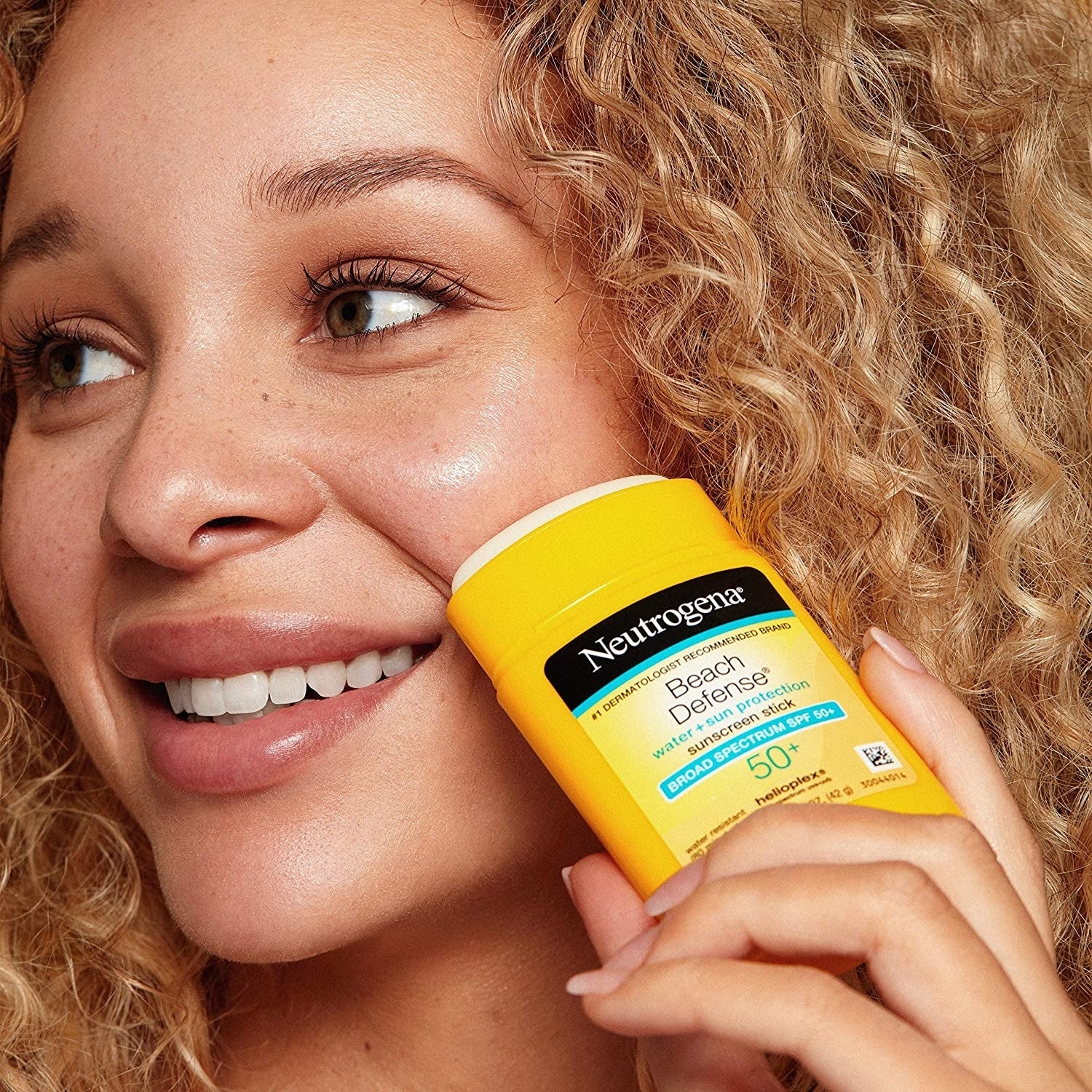 Woman smiling holding Neutrogena sunscreen, suggesting product for shopping