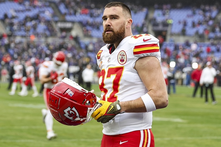 Kansas City Chiefs player holding a helmet walks on the field post-game