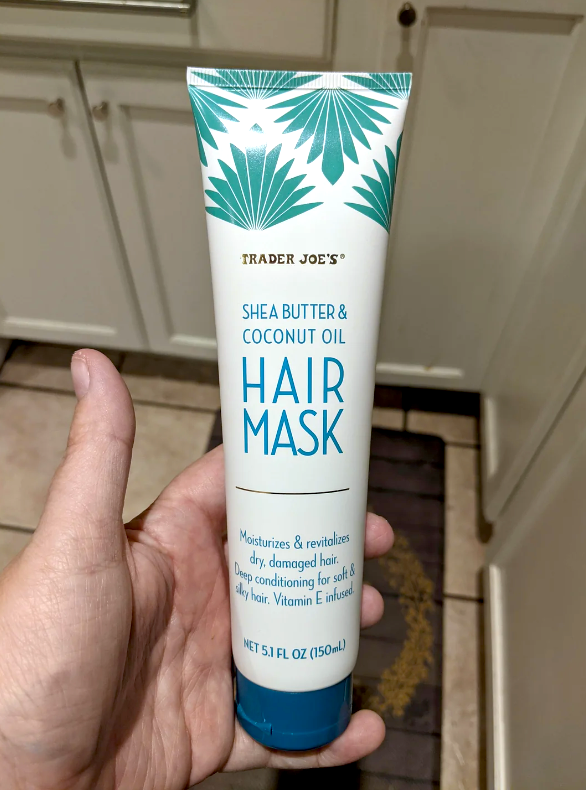 Person holding a Trader Joe&#x27;s Hair Mask tube with shea butter and coconut oil