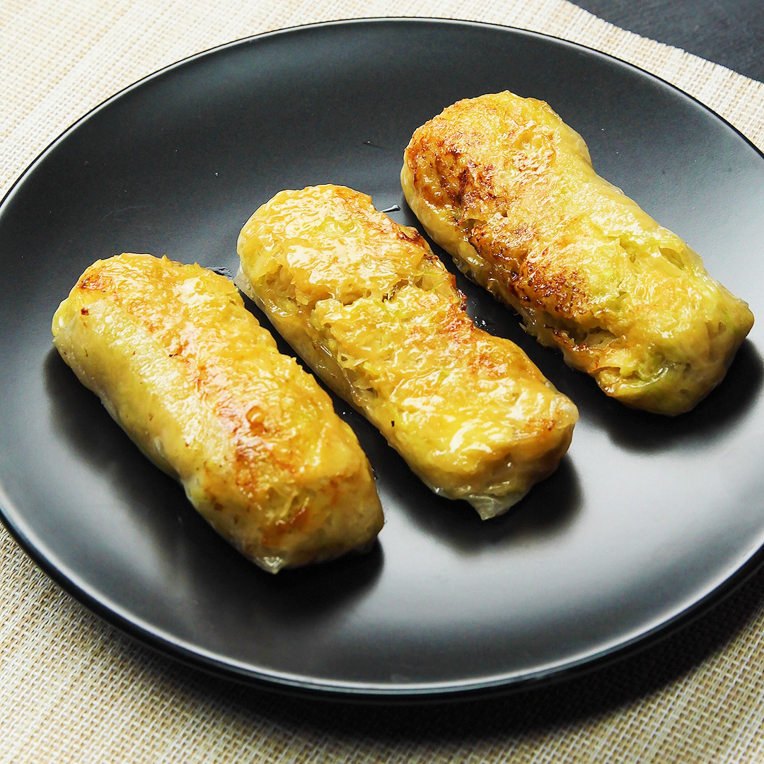 黒い皿の上に3つの焼き色のついたキャベマヨチーズのライスペーパー焼きが盛られている。